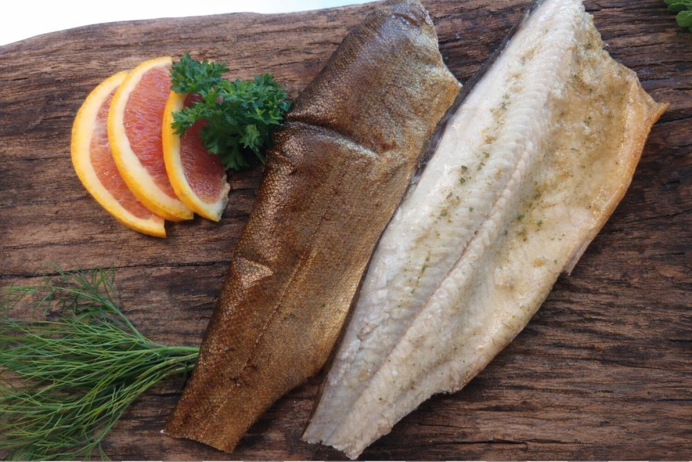 2 Forellenfilet auf einem Holzbrett mit Dill Petersilie und Blutorangenscheiben garniert